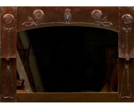 A Glasgow School Arts & Crafts enamel inset copper over mantle mirror
The arched plate flanked with shelves, the frame worked