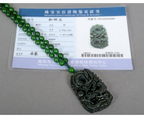A well carved green jade pendant
Decorated with a dragon chasing a flaming pearl, mounted on a green jade bead necklace; toge