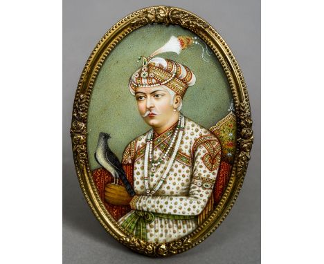 A 19th century Indian miniature portrait of a nobleman holding falcon
Housed in a gilt brass frame.  10 cm high. CONDITION RE