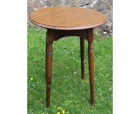 A 19th century Arts and Crafts oak lamp table, with circular top and arched sides, standing on splay legs with ring turned de