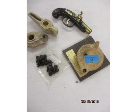 A lighter in the form of a pistol, grape shot from the West Indies, a soapstone lamp and two oil lamps, one bearing a reprodu