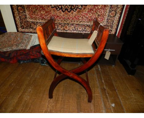 An early 20th century stained beach wood folding X-framed piano stool, with stuff over seat on shaped supports. H.71cm W.50cm