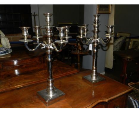 A pair of silver plate four branch five light candelabrum, with column supports, raised on stepped square base.