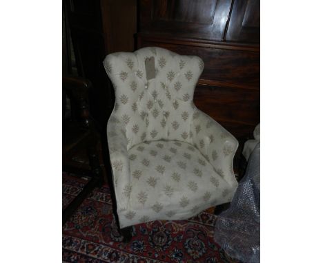 A late Victorian walnut framed low seat open armchair, with buttoned tapestry woven foliate cream upholstery, raised on turne