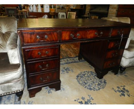 A George III style mahogany pedestal desk, having a gilt tooled brown leather skiver, above an arrangement of nine drawers, r