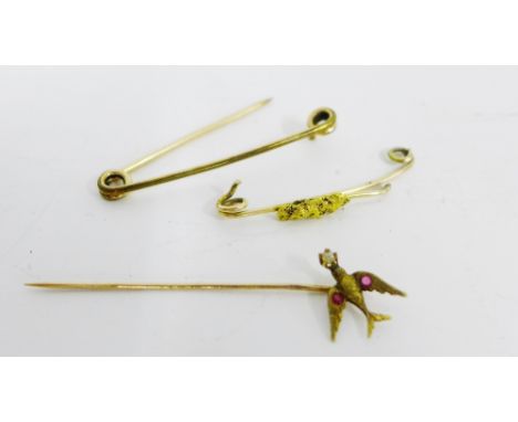 10 carat gold stick pin surmounted by a swallow with pearl and rubies and two other yellow metal brooches (3) 