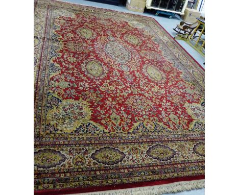 A Keshan Super carpet the red field with all over foliate pattern and multiple borders, 351cm x 534cm 