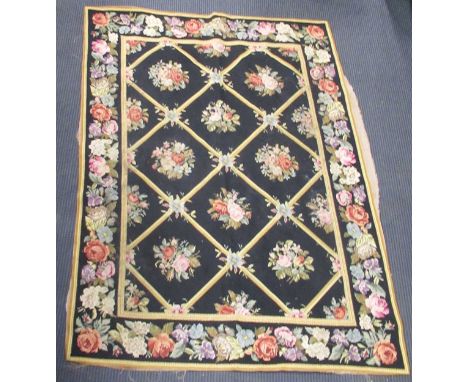 An English needlepoint tapestry floor covering, black ground, decorated with various flowers within a trellis pattern151 x 11