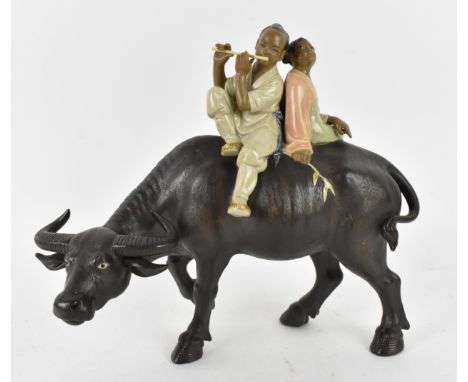 A 20th century Chinese shiwan glazed pottery model of  by Liu Zemian, modelled as a couple on the back of a water buffalo, th