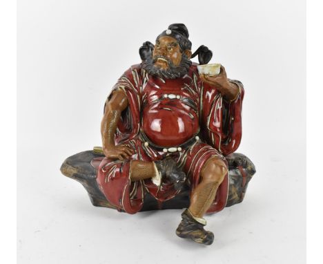 A large 20th century Chinese shiwan glazed pottery model of Zhong Kui by Liu Zemian, in a seated position holding a cup, with