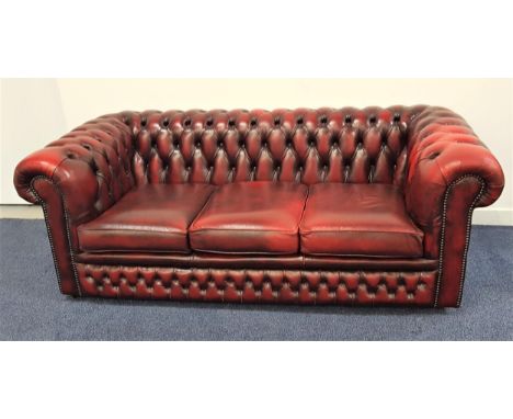 CHESTERFIELD SOFAin ox blood red leather with a button back and scroll arms with decorative stud detail, on casters, 190cm wi