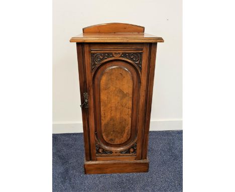 EDWARDIAN WALNUT BEDSIDE POT CUPBOARDwith a shaped arched raised back above a plain top with a carved panel door below, stand