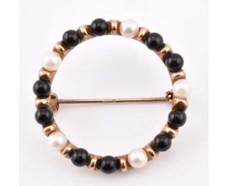 A hallmarked 9ct gold onyx and pearl brooch pin. The round brooch pin set with five pearls each interspersed by onyx spheres 