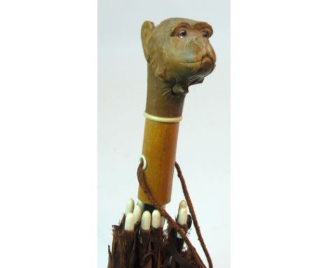 AN EARLY 20TH CENTURY PARASOL the handle carved with an articulated monkey head with a push-button which moves the mouth with