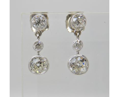 A PAIR OF DIAMOND DROP EARRINGS set in millgrained white metal settings, drop approx 1.7cm, estimated approx diamond content 