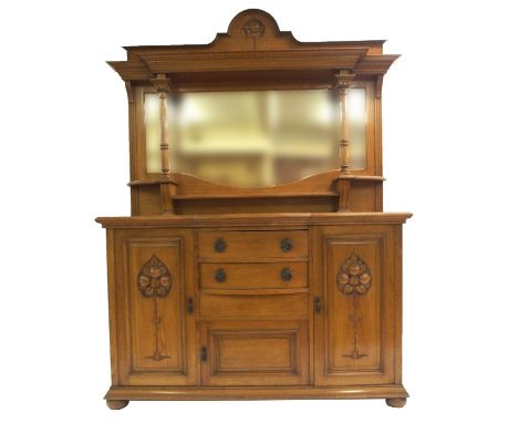 AN OAK ARTS AND CRAFTS MIRROR BACK SIDEBOARD with carved top above shaped mirror with pedestal supports and a base with two b