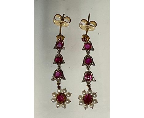 A pair of ruby and seed pearl floral drop earrings, each articulated drop of three ruby set links with inverted tulip head fr
