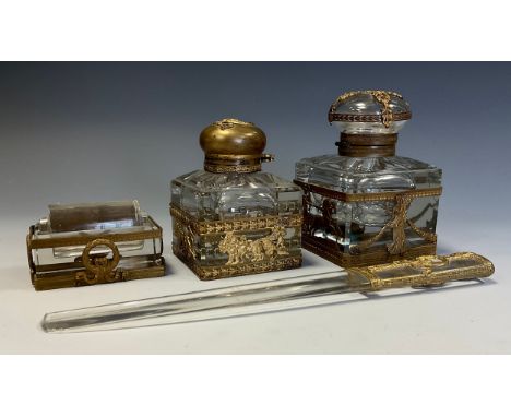 A neoclassical four piece desk set, two graduated inkwells, letter knife and roller, cast gilt metal mounts as Cherub Chariot