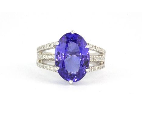 An 18ct white gold ring set with a 6.5ct oval cut richly coloured tanzanite and 0.35ct diamond shoulders, (O).