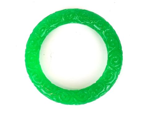 A Chinese carved green jade bangle width 13mm. Dia. 6cm.