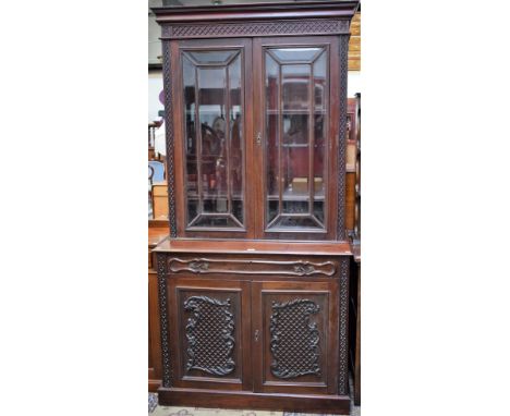 A late 19th/early 20th century mahogany library bookcase, outswept blind fretwork cornice above a pair of glazed doors enclos