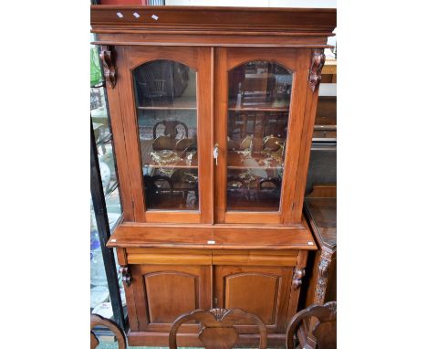 A Victorian style mahogany library bookcase, outswept cornice above a pair of glazed doors enclosing two adjustable shelves, 