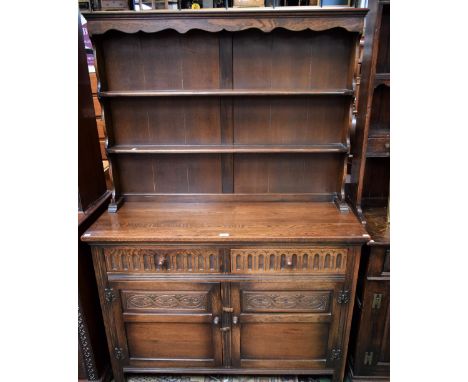 A 20th century oak dresser, outswept cornice above a pair of plate racks, the base with two short nulled drawers above a pair