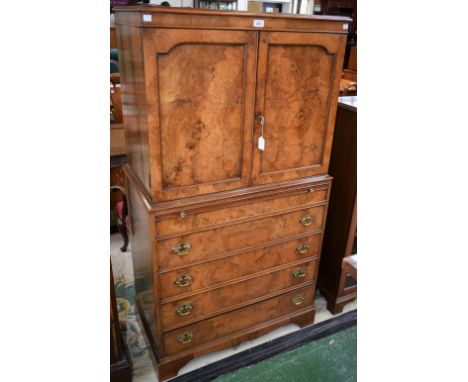 A George III style walnut side cabinet, rectangular top above a pair of panel doors enclosing a shelf, a slide and four long 