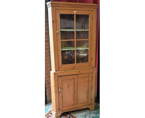 A pine Country kitchen corner cabinet, moulded cornice above a glazed door enclosing two shelves, the base with a cupboard do