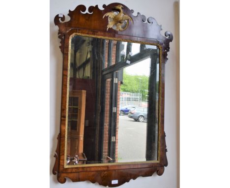 A George III style mahogany and parcel 'gilt' vauxhall looking glass, the bevelled rectangular plate crested by an avian, 116