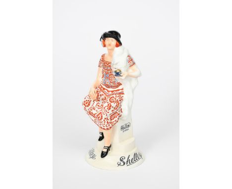 The Shelley Girl a rare Shelley Pottery advertising figure, modelled as a young lady in paisley dress and fox stole, resting 