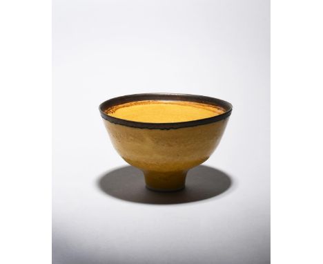 ‡ Dame Lucie Rie DBE (1902-1995) a porcelain footed bowl with bronze rim, covered to the foot with a mustard yellow glaze imp