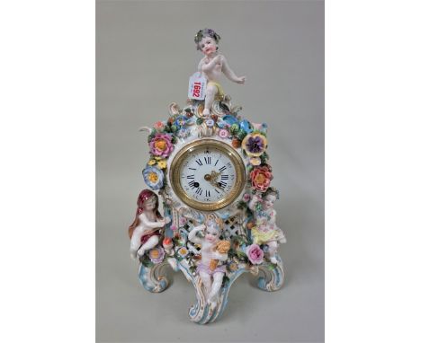 A large German porcelain mantel clock, decorated with flowers and cherubs, emblematic of the four seasons, 47cm high, (small 