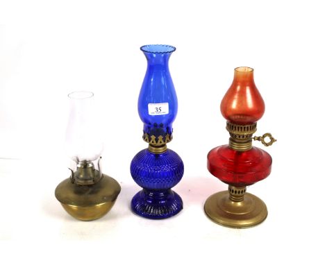 Two red and blue glass oil lamps and a small brass oil lamp