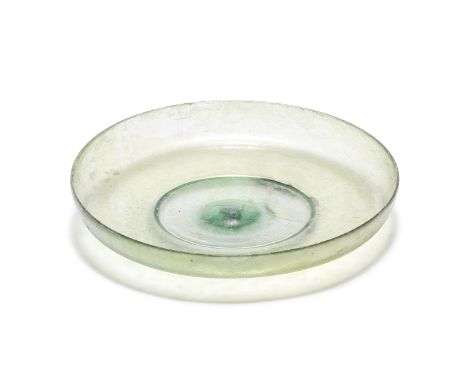  A Roman pale green glass footed dish circa 1st Century A.D.The shallow bowl with straight slightly flaring sides, on  a pede