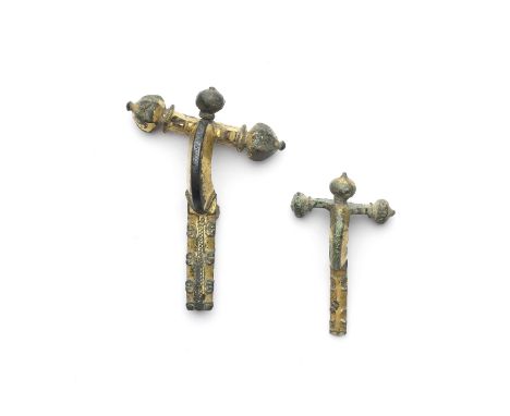  Two Roman gilt-bronze crossbow fibulae Circa 3rd-6th Century A.D.Both with three cupola-shaped terminals, the larger with mu