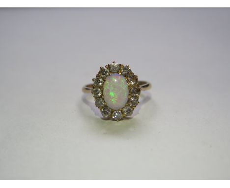 An opal and diamond set cluster ring, 14ct yellow shank and raised tapered shoulders to a centre oval cabochon cut opal in a 