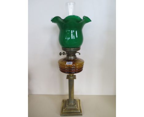 A brass oil lamp with amber coloured font and green shade, generally good, some denting to base 
