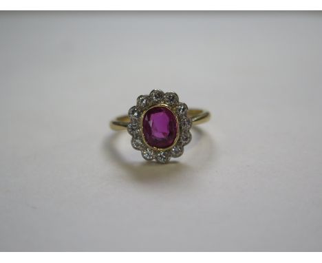 A ruby and diamond cluster ring, ruby approx 7mm oval, 18ct gold band, approx 3.8 grams, ring size N/O, Ruby has some surface