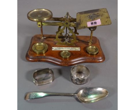 A set of brass postage scales, a silver tea spoon and two napkin rings, (qty). 