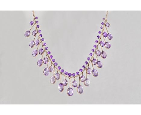 A gold and amethyst necklace, the front mounted with a row of circular cut amethysts above a two tier row of graduated oval c