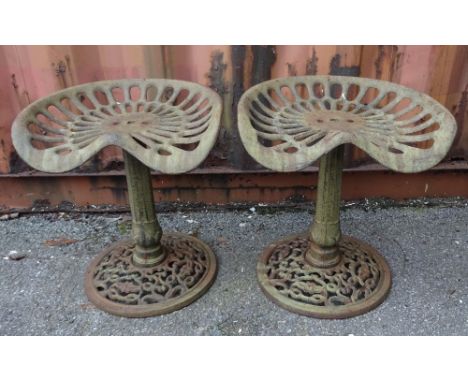 A pair of early 20th century cast iron stools previously tractor seats, 45cm wide x 49cm high (2).
