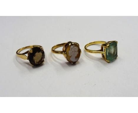 A gold ring, claw set with a rectangular step cut aquamarine, a 9ct gold ring, claw set with an oval cut smoky quartz and a g