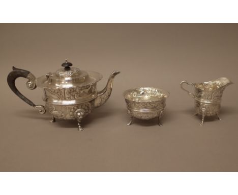 A silver three piece teaset, comprising; a teapot, a sugar bowl and a milk jug, each piece embossed with flowers and animals 