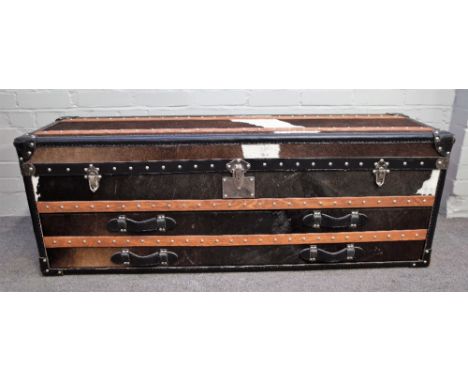 A 20th century cow hide and leather upholstered travelling trunk, with fitted interior for shoes etc., 141cm wide x 50cm high