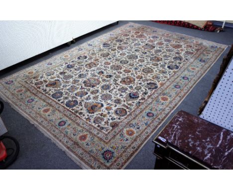 An Isfahan carpet, Persian, the ivory field with a small central roundel, with bold floral and palmette sprays; a grey palmet