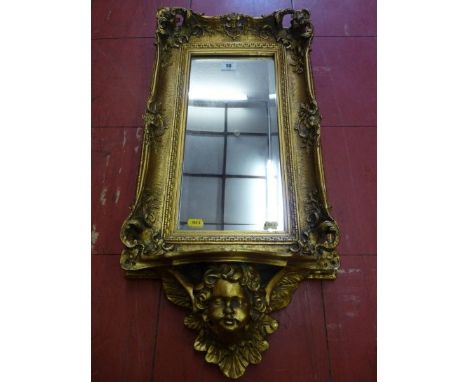 A REPRODUCTION GILT FRAMED WALL MIRROR with rectangular bevelled glass in a deep swept Rococo style frame with lower shelf an