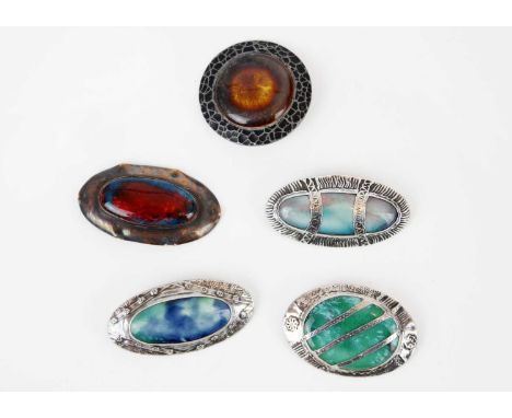 A collection of five Arts & Craft Ruskin style enamel brooches. One with hammered mount stamped 'HAND WROUGTH' and monogramed