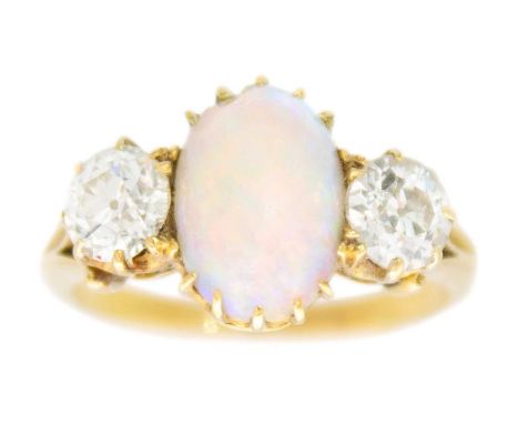 An 18ct diamond and white opal set three-stone ring. The two old round brilliant cut diamonds each of 0.50ct approximately, f