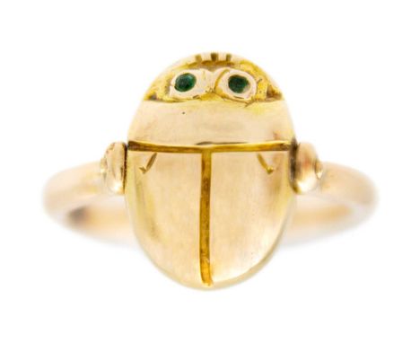 A high purity gold (tests 14ct) Egyptian Revival scarab beetle swivel ring. The eyes set with small round cut emeralds, the h